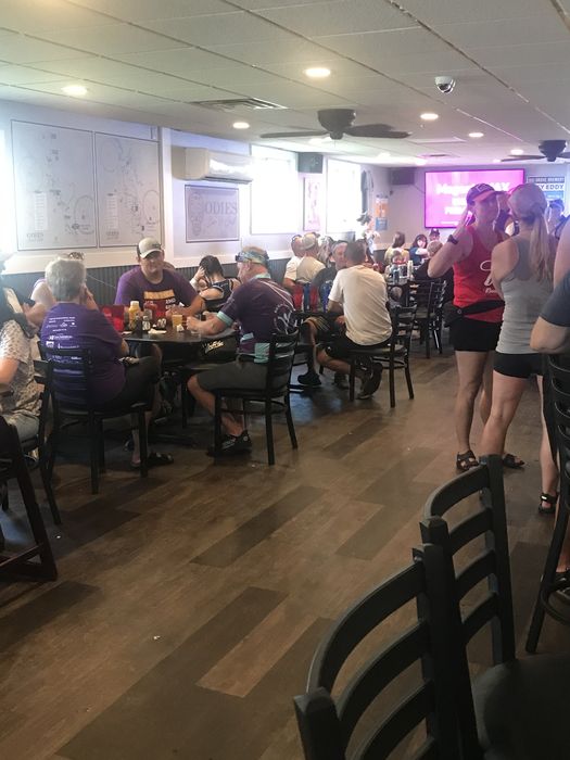 A packed dining room full of riders, with route maps on the wall